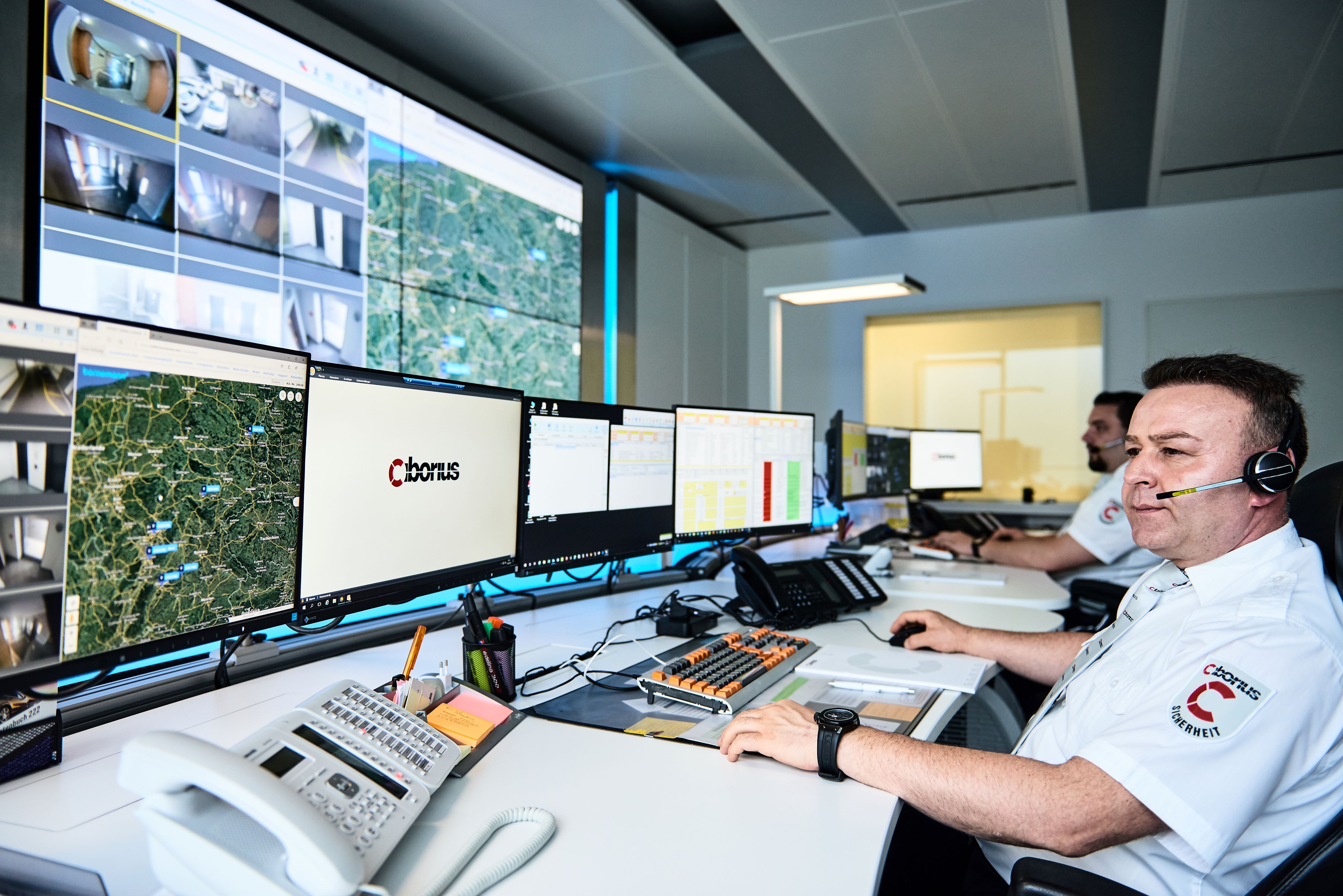 CIBORIUS Mitarbeiter mit Headset an einem Leitstellenplatz vor mehreren Monitoren mit Kamerabildern und Kartenansichten